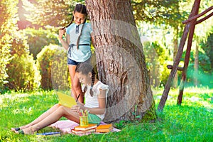 Two pretty little girls reading in park