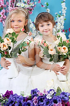 Two pretty little girls in white dresses hold