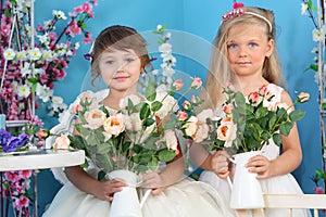 Two pretty little girls in white dresses hold