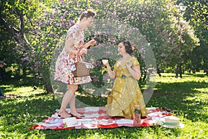 Two pretty pin up ladies having nice picnic in the city park in a sunny day together. girls friends enjoy hot summer weather. beau