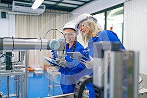 Two pretty professional technician or engineer women help to check the system use controller and ipad with robotic machine in