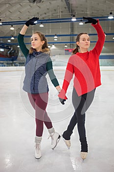 Two pretty slim graceful girls pose on skate in photo