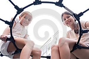two pretty teen girls playing on a modern playground in identical clothes. sister, bffs. sisterhood, friendship.
