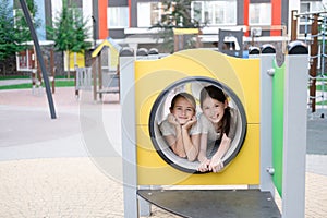 two pretty teen girls playing on a modern playground in identical clothes. sister, bffs. sisterhood, friendship. photo