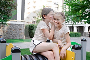 two pretty teen girls playing on a modern playground in identical clothes. sister, bffs. sisterhood, friendship. photo