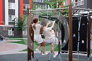 two pretty teen girls playing on a modern playground in identical clothes. sister, bffs. sisterhood, friendship. photo