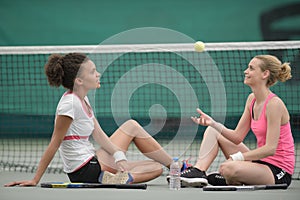 Two pretty tennis players sitting on court after match