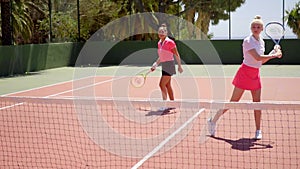 Two pretty women playing a game of tennis doubles