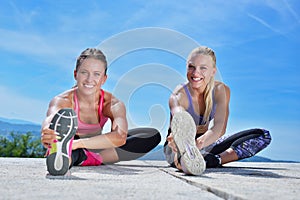 Two pretty women stretching in a park before starting a workout session