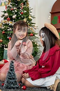 Two pretty young Asian girls are enjoying playing in the living room on a Christmas night together