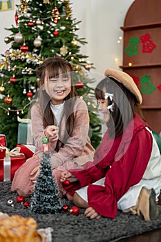Two pretty young Asian girls are enjoying playing in the living room on a Christmas night together