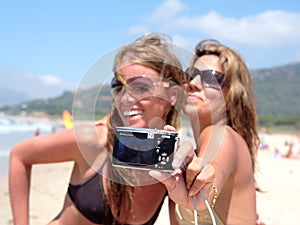 Two pretty young girlfriends taking a photo of themselves with c