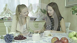 Two pretty young smiling girl friends having relaxing time at dining table