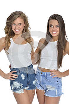 Two pretty young women pose in white tanks and denim