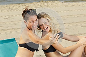 two pretty young women taking selfie by sea