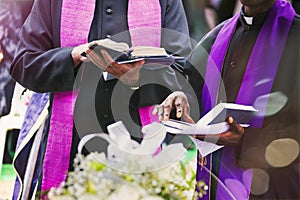 two priests reading prayers from the bible at a funeral