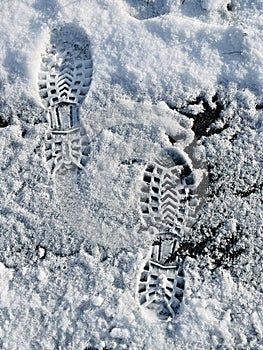 Two prints of shoes on snow.