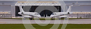 Two private planes in front of a hangar photo