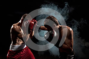 Two professional boxer boxing on black smoky background,