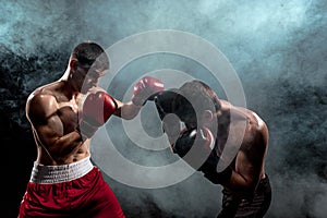 Two professional boxer boxing on black smoky background,