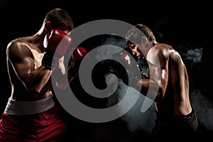 Two professional boxer boxing on black smoky background,