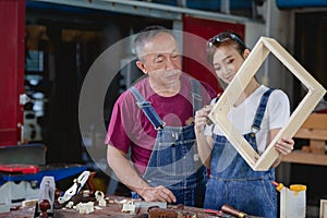 Two professional carpenters works in her own woodworking shop. Carpenter work on wood plank in workshop. small business concept