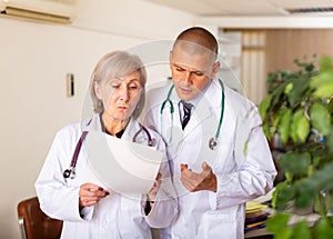 Two professional doctors discussing medical card of patient