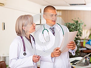 Two professional doctors discussing medical card of patient