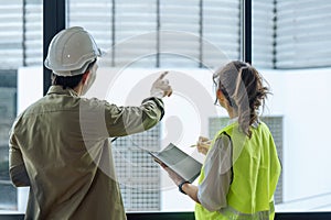 Two professional engineer and architect in safety helmet working together at construction site