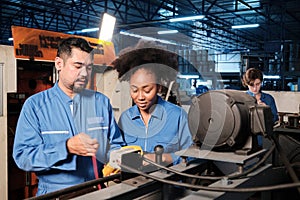 Two professional engineers inspect machines` electric systems at the factory