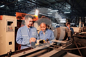 Two professional engineers inspect machines` electric systems at the factory