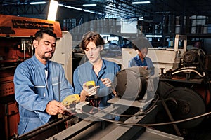 Two professional engineers inspect machines` electric systems at the factory