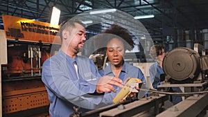 Two professional engineers inspect machines` electric systems at the factory.