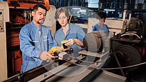 Two professional engineers inspect machines` electric systems at the factory