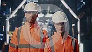 Two professional engineers posing at production workshop in uniform close up.