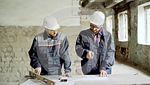 Two professional engineers working together at the desk with building documentation on construction area.