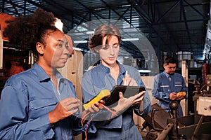 Two professional female engineers inspect machines` electric systems at factory