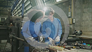 Two professional female workers work in the metalwork manufacturing factory.