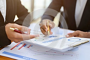 Two professional financial analysts or accountant reviewing financial graphs on the report together