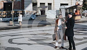 Two professional men engaging in a casual conversation outdoors in a city setting.