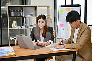 Two professional and smart Asian female and male financial analysts working together