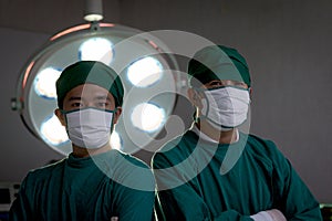 Two professional surgeon doctor standing under bright light, using surgical equipment to do surgery at hospital operating room.