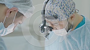 Two professional surgeons on operation. Action. Surgeons calmly and intently perform operation with anesthesia. Surgeons