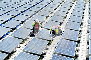 Two professional technician workers with safety uniform work with solar cell panels system to check and maintenance over water