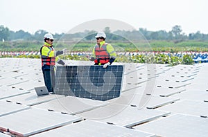 Two professional technician workers stand and hold solar cell panel also discuss together in area of network of base over area of