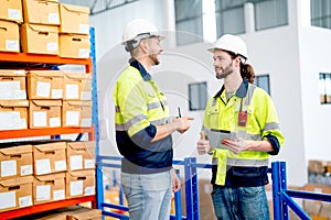 Two professional warehouse worker men hold tablet and discuss about work together also stay in front of shelves with product boxes