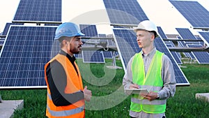 Two professional white engineers discuss the plan to install the new solar panels.