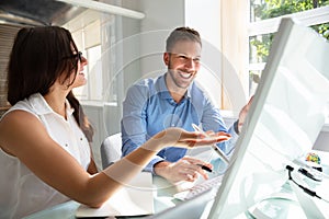 Two Businesspeople Looking At Computer Having Conversation