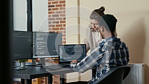 Two programmers doing high five hand gesture at desk with multiple screens running code celebrating