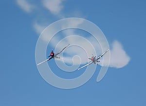 Two propeller airplanes trailing smoke and diving in a simulated attack
